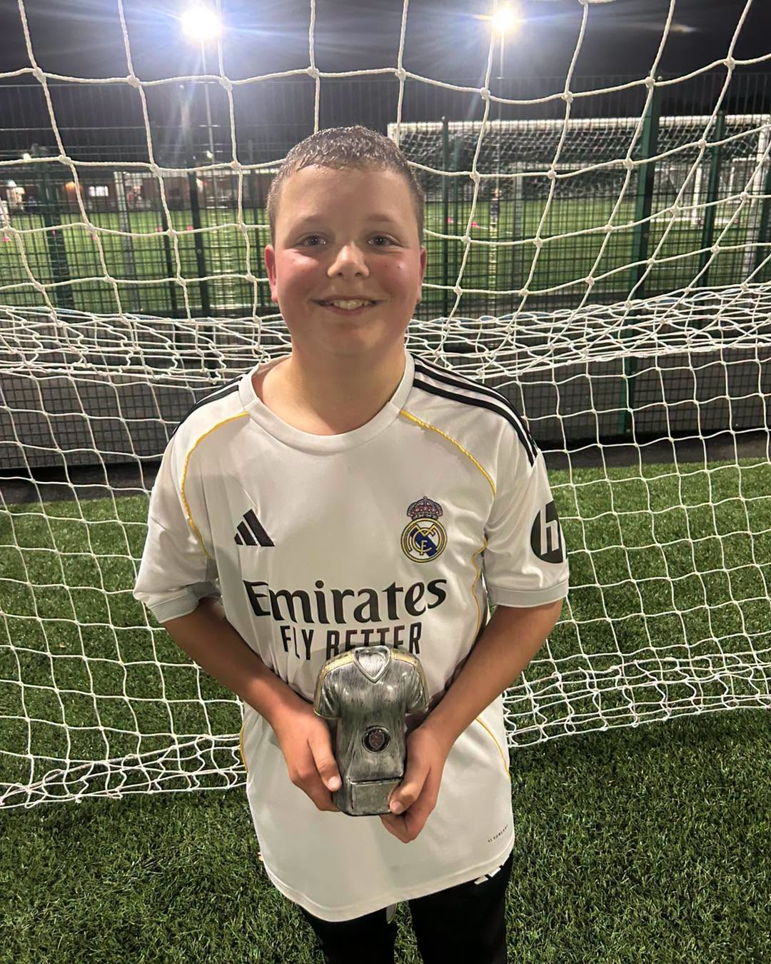 Young footballer proudly holding his Player of the Session trophy